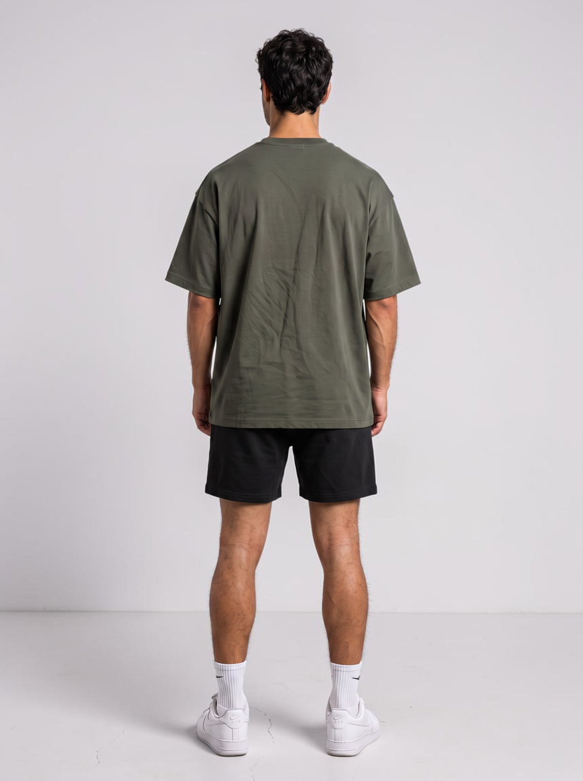Back view of a man wearing an Ambition Limitless olive green oversized organic cotton t-shirt with dropped shoulders.