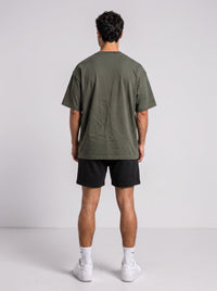 Back view of a man wearing an Ambition Limitless olive green oversized organic cotton t-shirt with dropped shoulders.