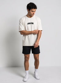 Ambition Limitless oversized off-white organic cotton t-shirt with black logo on chest worn by a male model