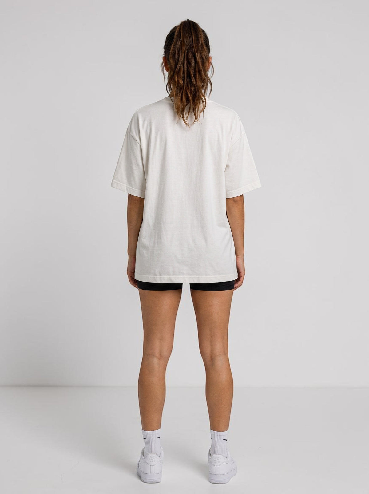 Back view of a woman wearing an Ambition Limitless oversized white organic cotton t-shirt with dropped shoulders.