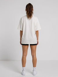 Back view of a woman wearing an Ambition Limitless oversized white organic cotton t-shirt with dropped shoulders.